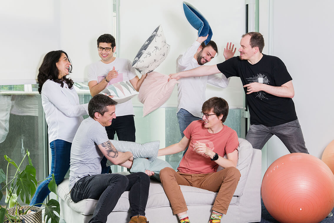 Huit personnes assises les uns à côté des autres en train de s'amuser en faisant une bataille de polochons