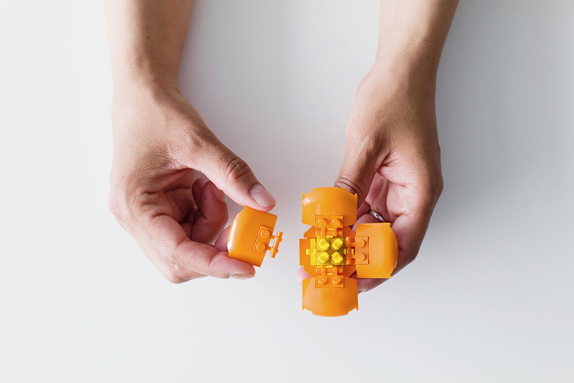 Deux mains qui assemblent une fleur en Lego