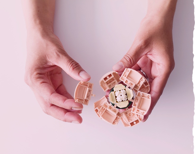 Deux mains qui assemblent une fleur en Lego